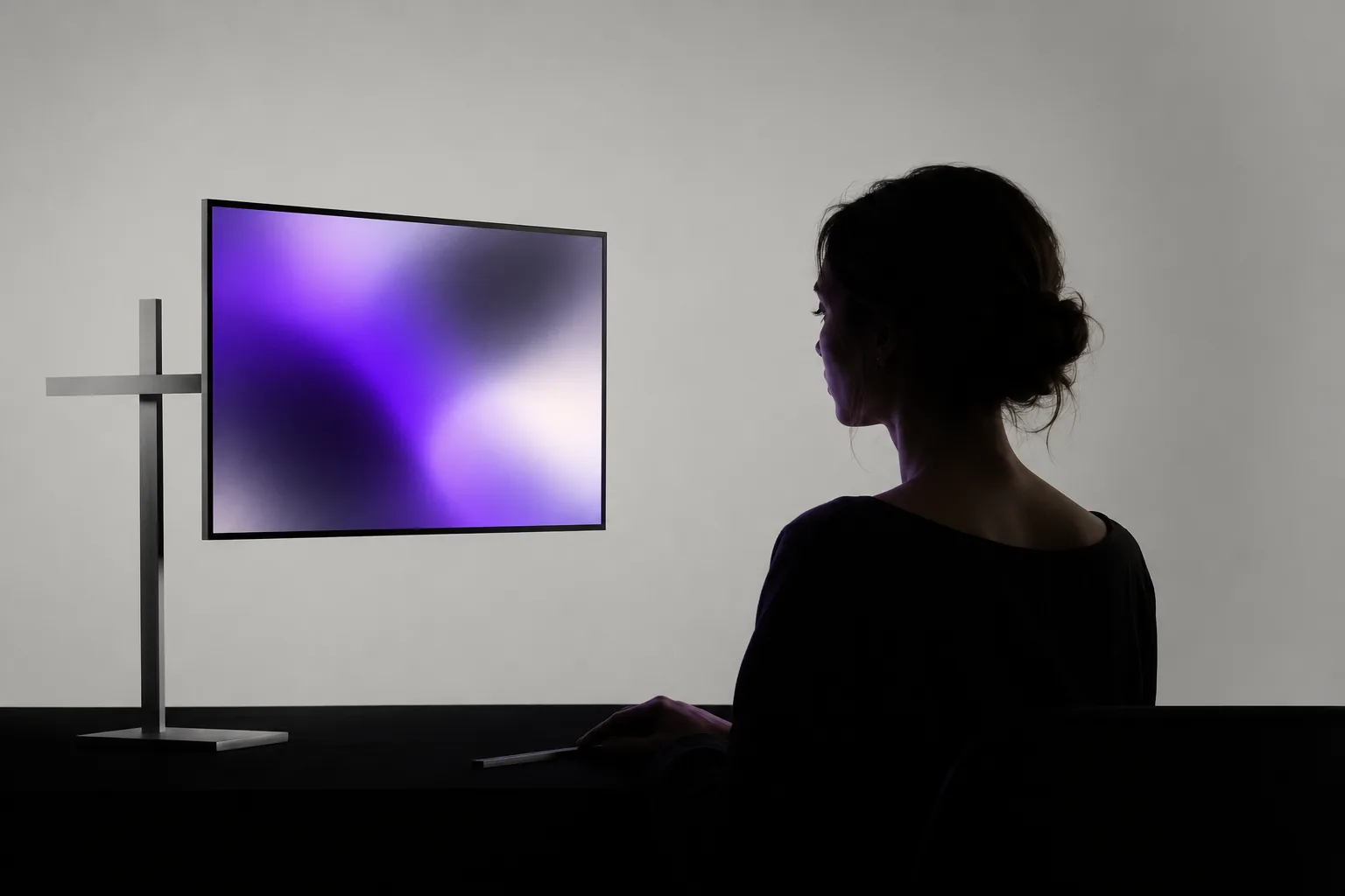 Concept image of a silhouetted person observing a blurred purple gradient on a monitor