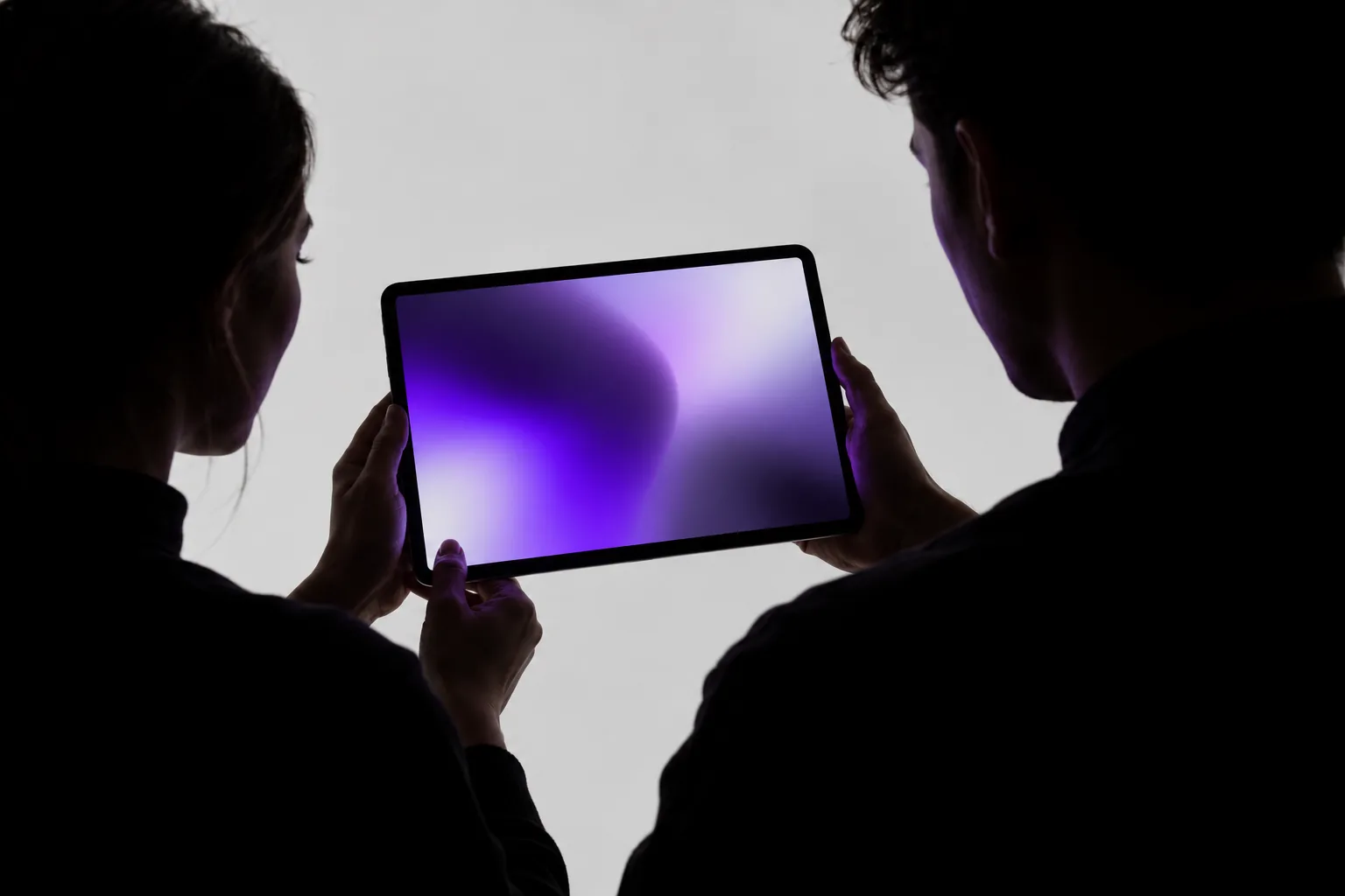 Concept image of two silhouetted people collaborating in controlled purple light
