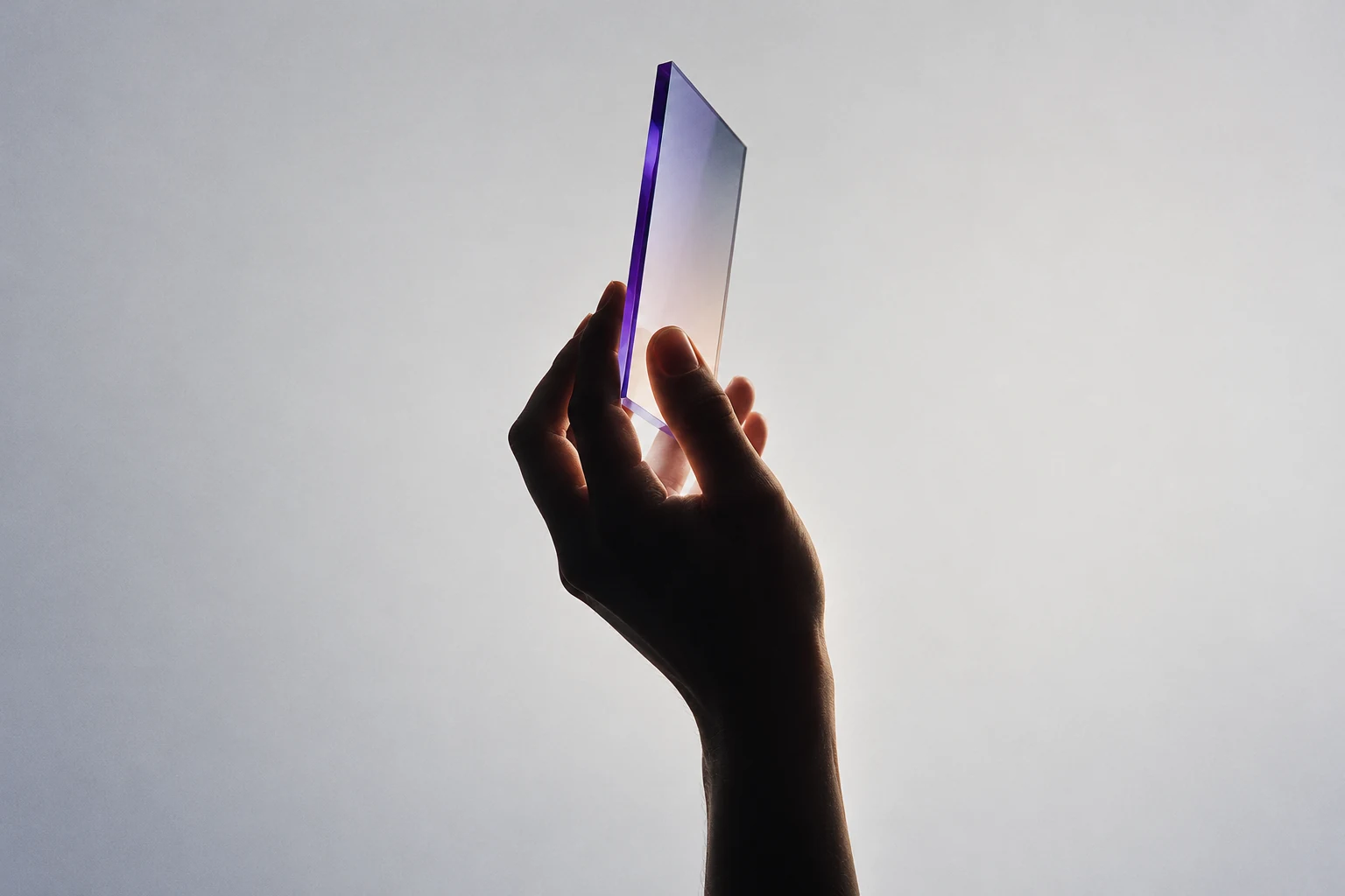 Concept image of a hand holding a slim optical glass plane with a restrained purple edge light