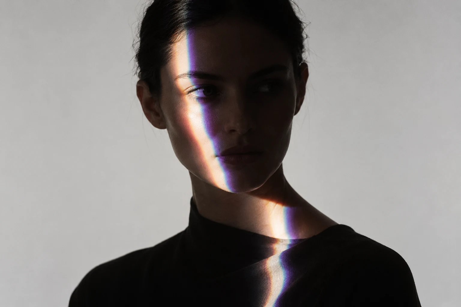 Concept image of a dark portrait lit by a narrow prismatic band of light