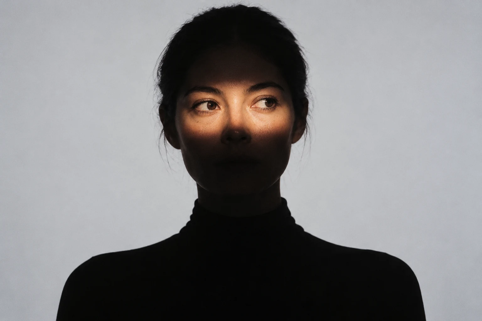 Concept image of a woman in silhouette with a controlled band of light revealing her eyes
