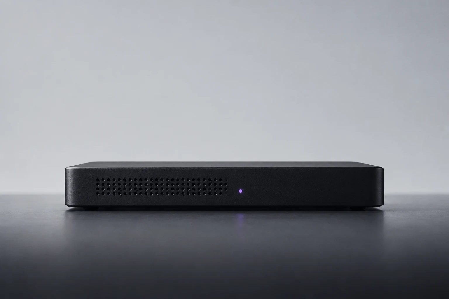 Matte-black server unit on a cool-grey surface with a restrained purple status light