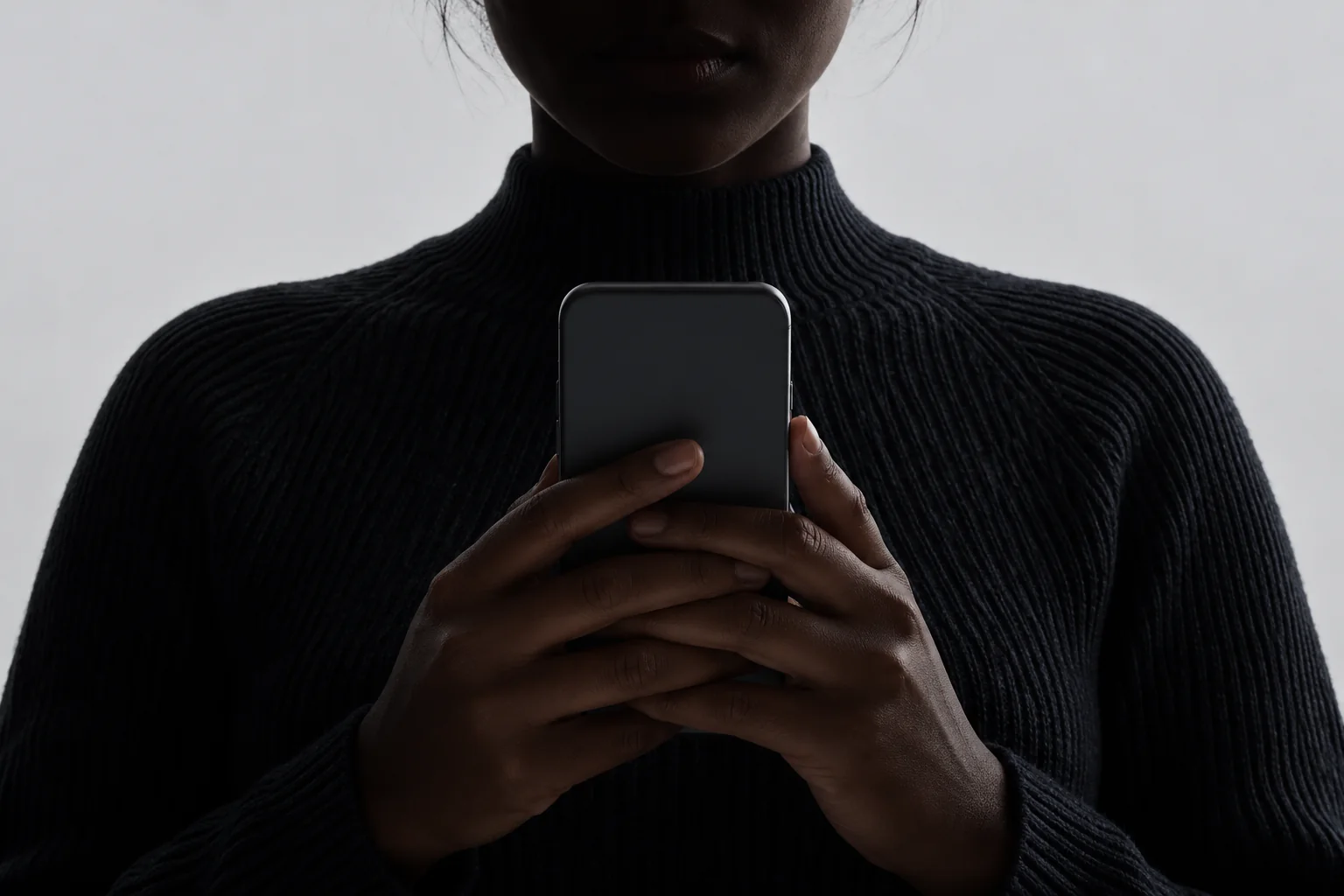 A person holding a dark phone in shadow, representing a system built around the business