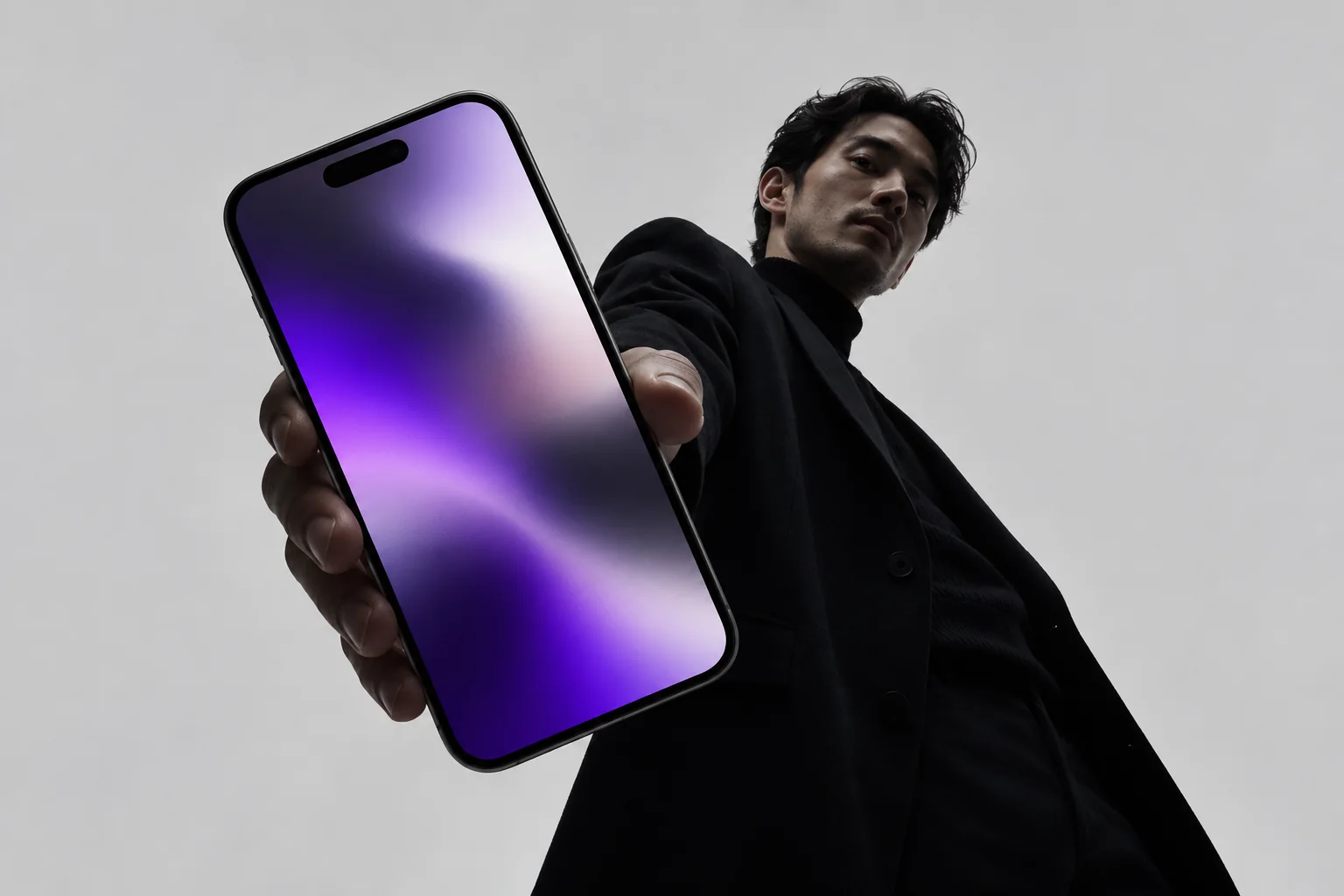 A person presenting a front-facing phone with a restrained purple screen, representing clearly labelled digital production