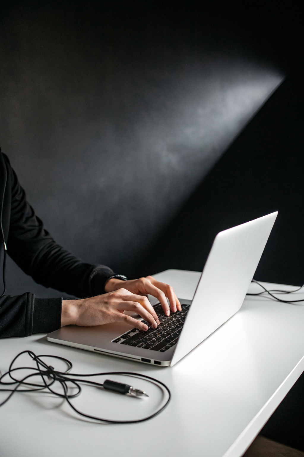 Person typing on laptop in dark minimalist studio, representing creative AI workflows