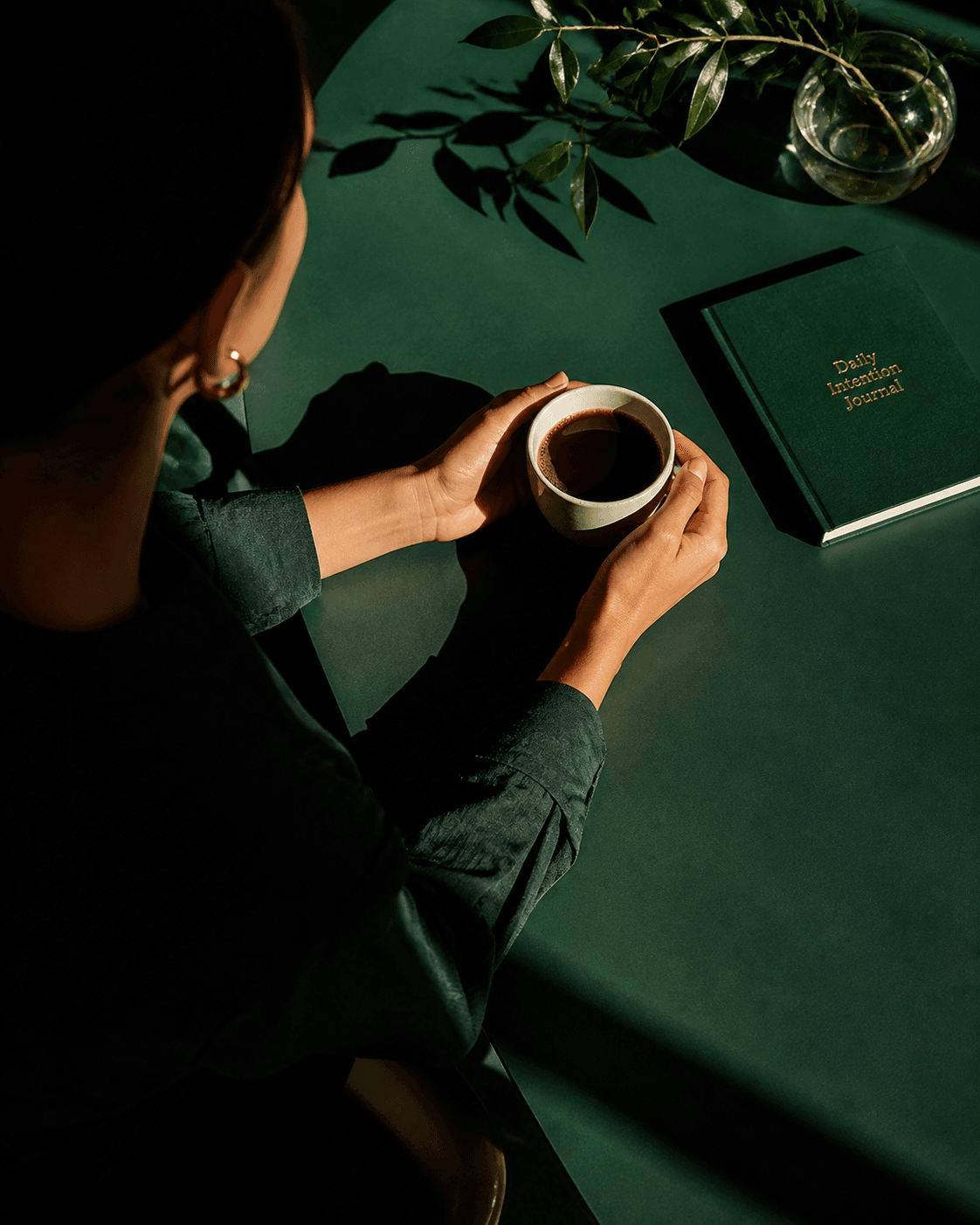 Person at green table with coffee and notebook, warm editorial lifestyle