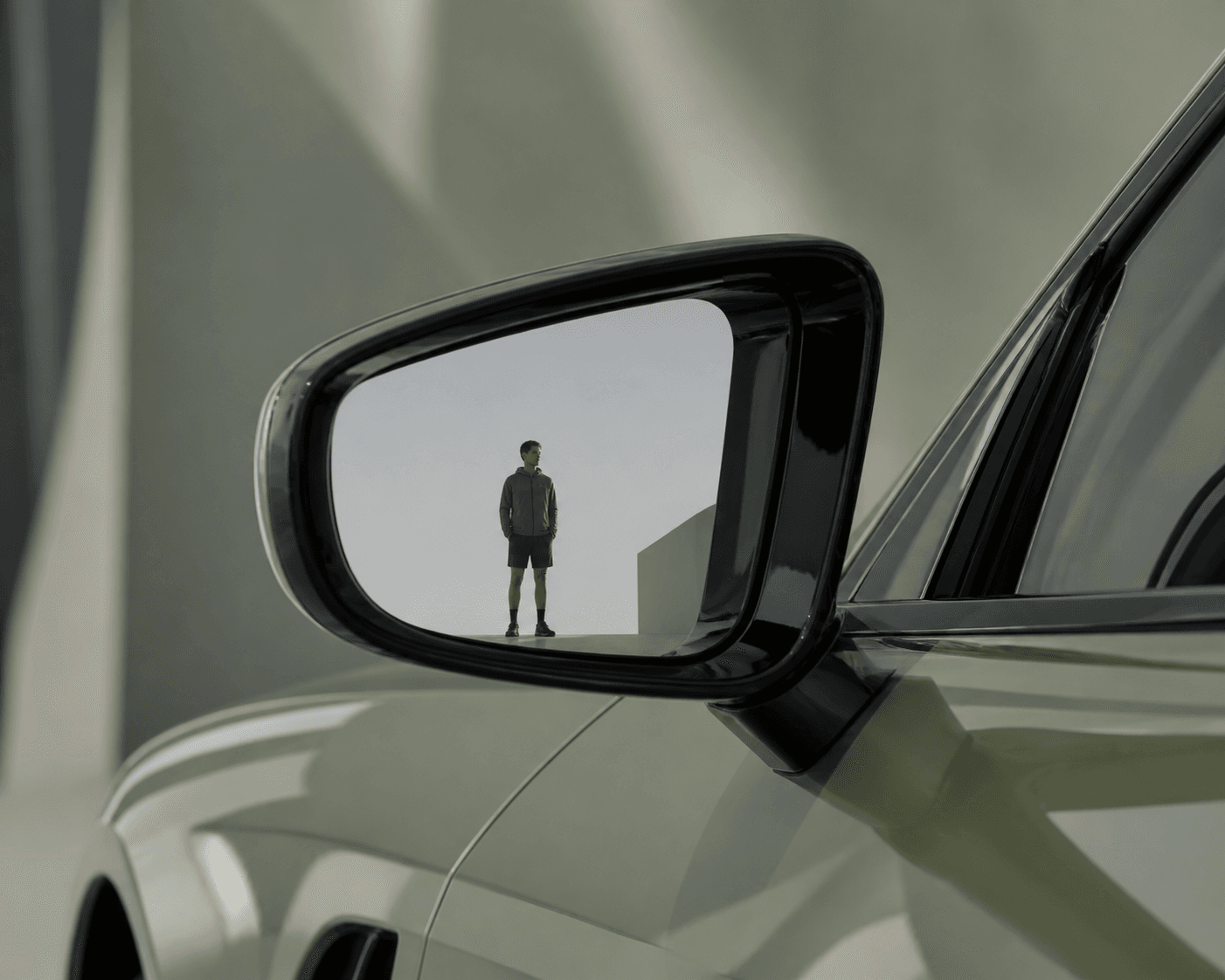 Car mirror reflecting a distant figure, muted olive green editorial product photography